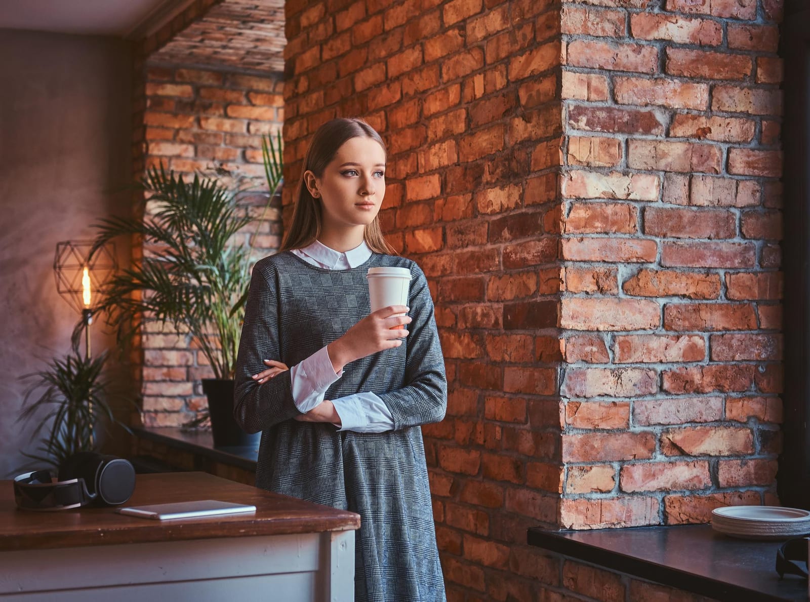Mulher segurando um copo de café para viagem em ambiente aconchegante