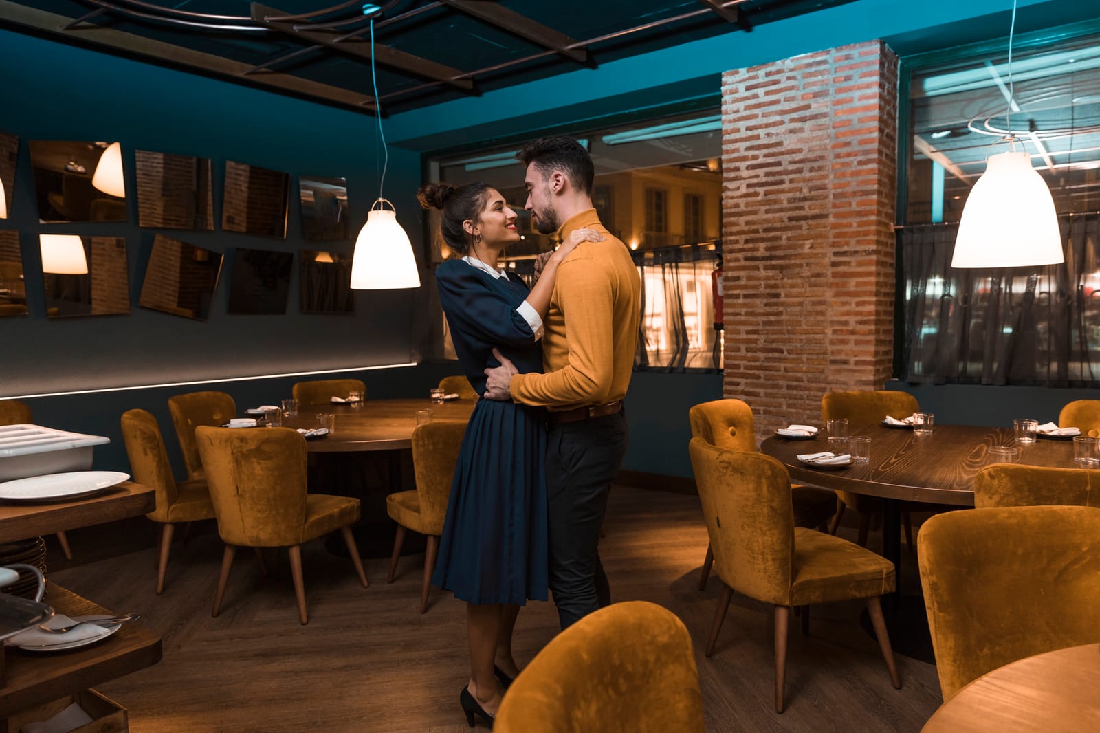 Casal comemorando em mesa de restaurante com abraço descontraído